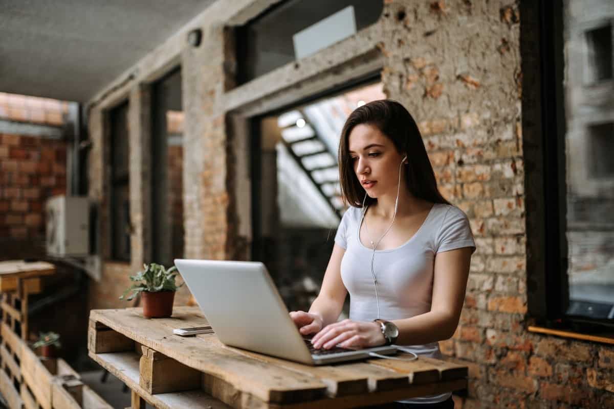 Woman blogger using laptop and wearing earphones